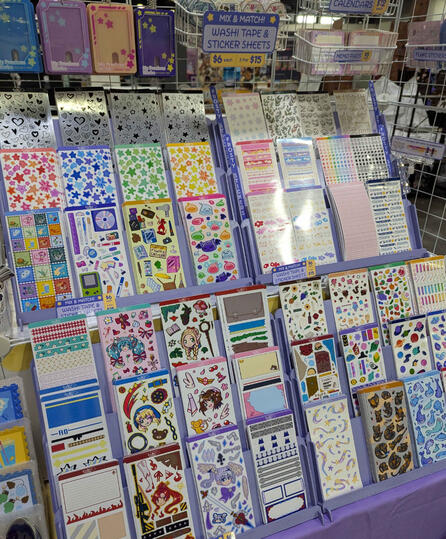 Table closeup May 2026 - sticker sheets, keychains, memo pads